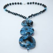 Un collier avec pendentif composé de trois perles plates.