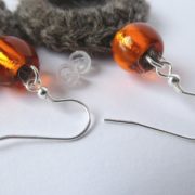 Détail des crochets d'oreilles laine et perle orange.