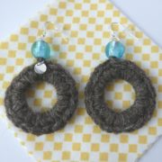 Boucles d'oreilles en laine posées sur la lingette d'entretien.
