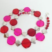 Le collier rouge et rose fluo a aussi des perles métalliques.