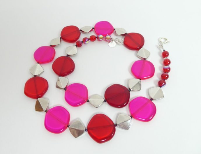 Le collier rouge et rose fluo a aussi des perles métalliques.