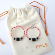 Les boucles d'oreilles noires, rouges et roses sur leur pochon en flanelle.