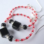 La perle cube noire des boucles d'oreilles noires, rouges et roses.