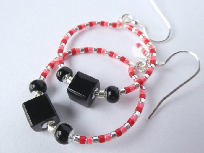 La perle cube noire des boucles d'oreilles noires, rouges et roses.