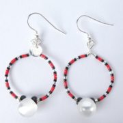 Les boucles d'oreilles blanc nacré, rouges et noires ont une perle bouton.