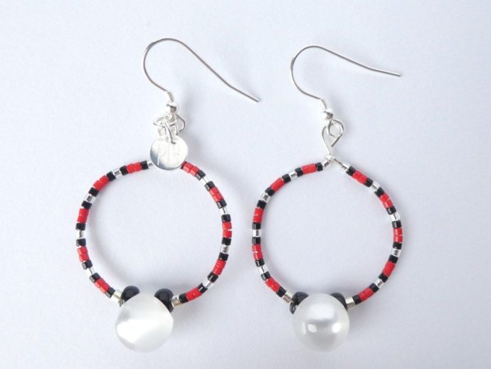 Les boucles d'oreilles blanc nacré, rouges et noires ont une perle bouton.