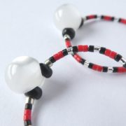 La perle bouton des boucles d'oreilles blanc nacré, rouges et noires.