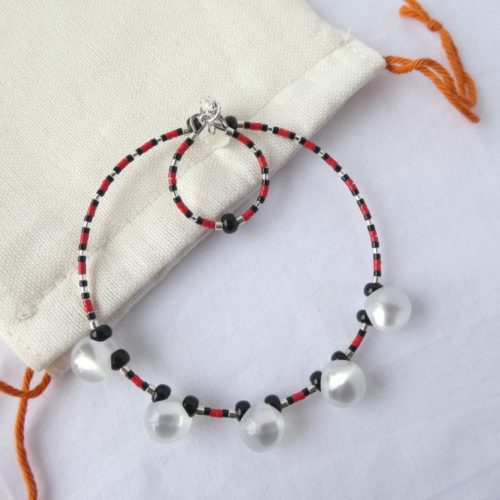 Le bracelet blanc nacré, rouge et noir et son pochon en coton.