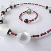 Gros plan sur les perles du bracelet blanc nacré rouge et noir.