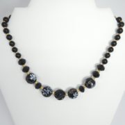 Le collier noir et or sur son présentoir.