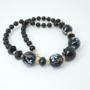 Les perles rondes en verre du collier noir et or.