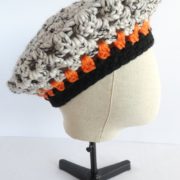 La rayure orange du béret noir et blanc.