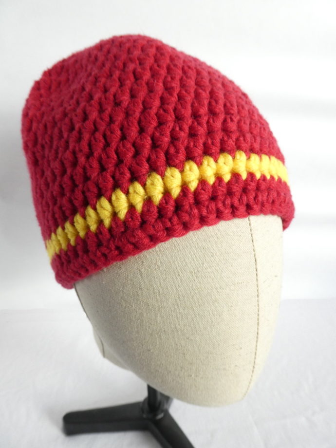 Un bonnet crocheté en laine rouge avec une rayure jaune.
