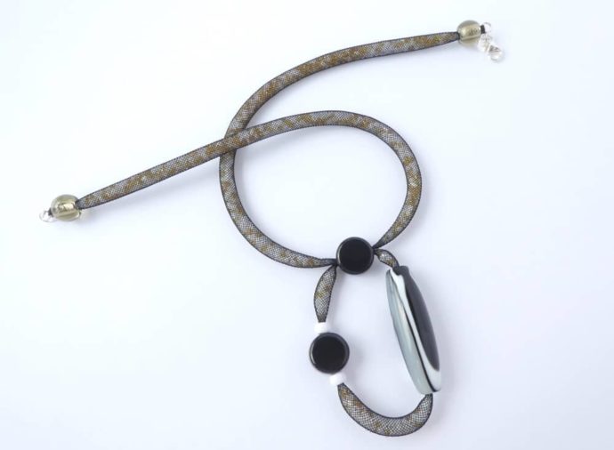Le pendentif asymétrique du collier en résille tubulaire noire.