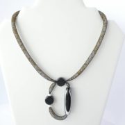 Le collier avec pendentif en résille tubulaire noire.