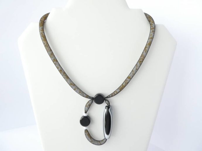 Le collier avec pendentif en résille tubulaire noire.