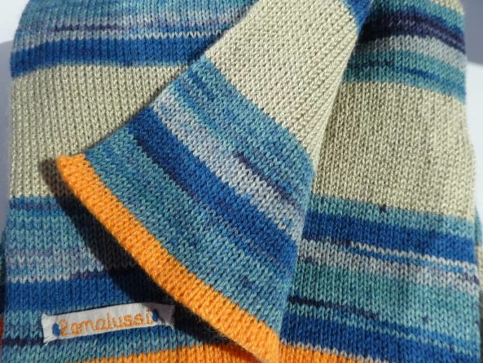 Au bord de l'écharpe en laine chanvre et bleues quelques rangs en orange.