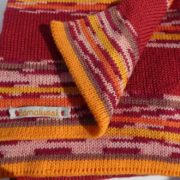 L'écharpe en laine à rayures rouges a aussi du orange, du jaune et du rose.