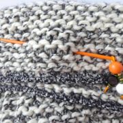 Le bijou d'écharpe orange piqué dans une grosse écharpe.