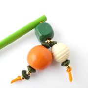 Gros plan sur les perles en bois du bijou d'écharpe vert.
