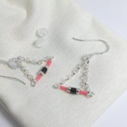 Les embouts et le pochon en coton des boucles d'oreilles roses avec chaîne argent.