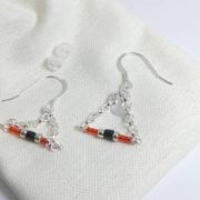 Les embouts et le pochon en coton des boucles d'oreilles rouges avec chaîne argent.