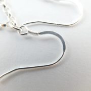 Gros plan sur les crochets des boucles d'oreilles roses avec chaîne argent.