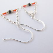 Gros plan sur les crochets d'oreilles des boucles rouges avec chaîne argent.