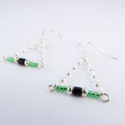 Gros plan sur les perles Miyuki des boucles d'oreilles vertes avec chaîne argent.