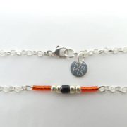 Le fermoir Menotte et la marque PMLS du bracelet rouge avec chaîne argent.
