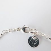 Gros plan sur le fermoir Menotte du bracelet vert avec chaîne argent.
