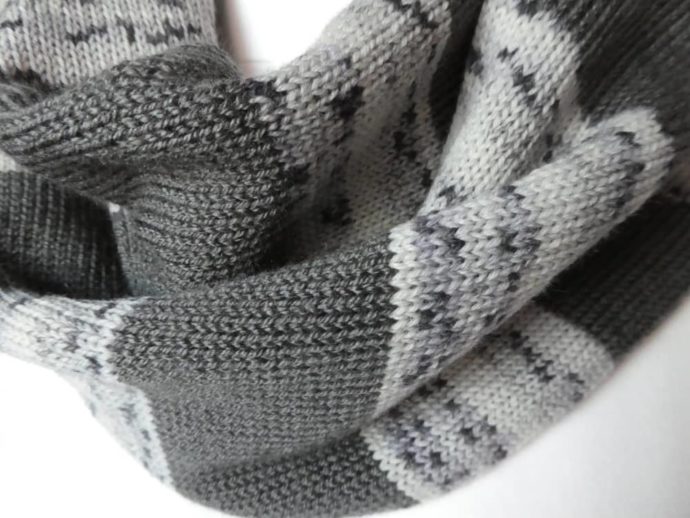 Gros plan sur la laine fine de l'écharpe à rayures grises.