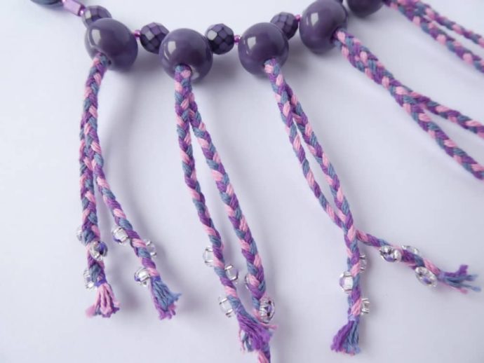 Des perles translucides sont cousues sur le cordon du collier Valentine lilas rose.