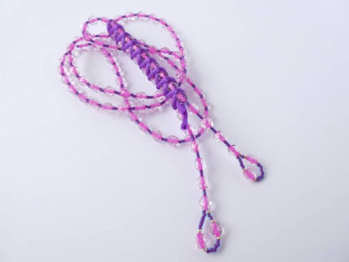 Le long collier rose et violet avec son cordon en queue de rat violet.