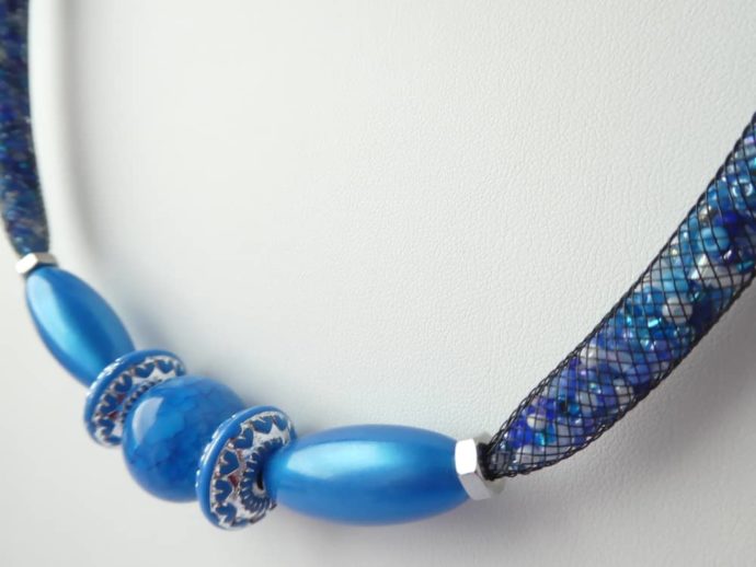 Jolie couleur pour ce collier en résille tubulaire noire garnie de perles bleues et blanches.