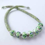 Les écrous en inox donnent un éclat facetté au collier vert blanc bleu.