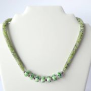 Le collier en résille vert blanc bleu de chez Pamalussi sur un présentoir.