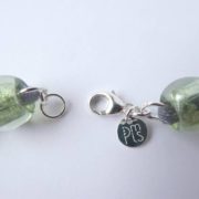 La marque PMLS et le fermoir du collier en résille vert blanc bleu.