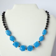 Le collier Garance bleu et noir sur un présentoir.