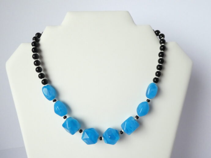 Le collier Garance bleu et noir sur un présentoir.