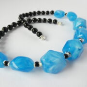 Gros plan sur les perles en résine bleue du collier Garance bleu et noir.