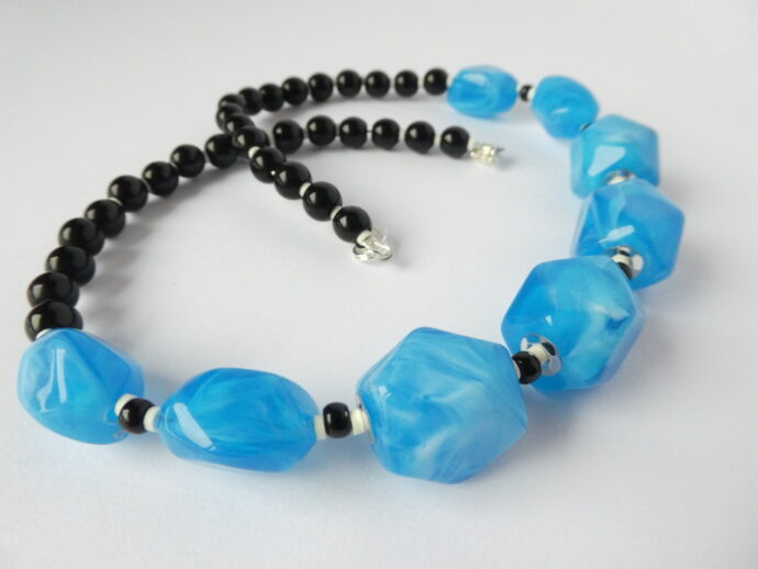 Gros plan sur les perles en résine bleue du collier Garance bleu et noir.