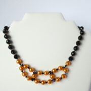 Le collier Inès or et noir sur un présentoir.