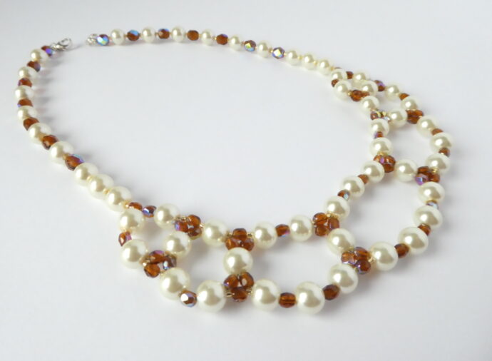 Les perles tissées du collier Chloé nacre et ambre.