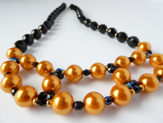 Le tissage des perles en verre du collier Inès or et noir.