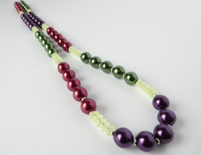 Les perles pourpres, violettes et vertes du collier Romy de chez Pamalussi.