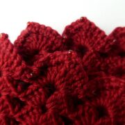 Gros plan du point crocheté et des perles des manchettes rouges.