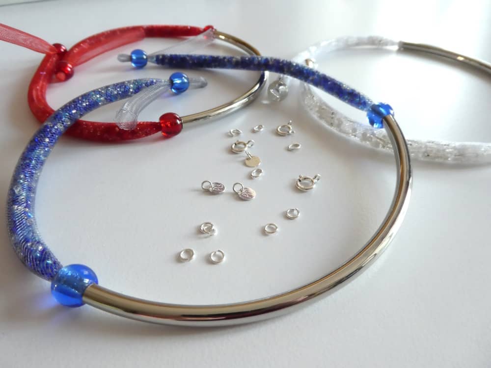 Les trois colliers bleu blanc rouge en résille tubulaire et tube en métal argenté.