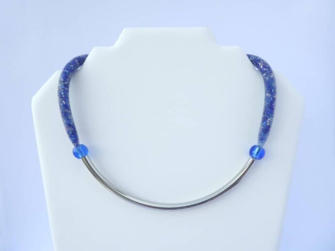 Le collier bleu en résille tubulaire Bertille sur le présentoir.