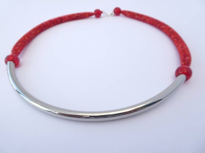Le collier rouge Rudy est composé d'une résille tubulaire garnie de rocailles et d'un tube courbé en métal.